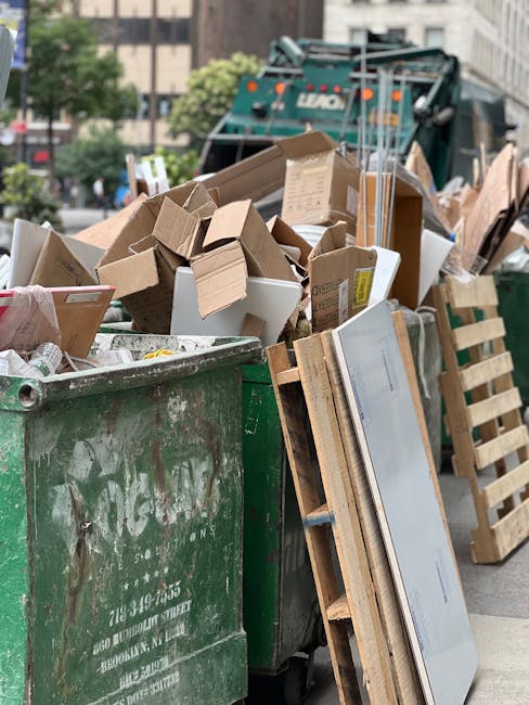 Four large blue rubbish bags filled with waste are positioned on the pavement next to the rear of a white commercial van, which is parked outside a building with a glass entrance. The bags appear to b